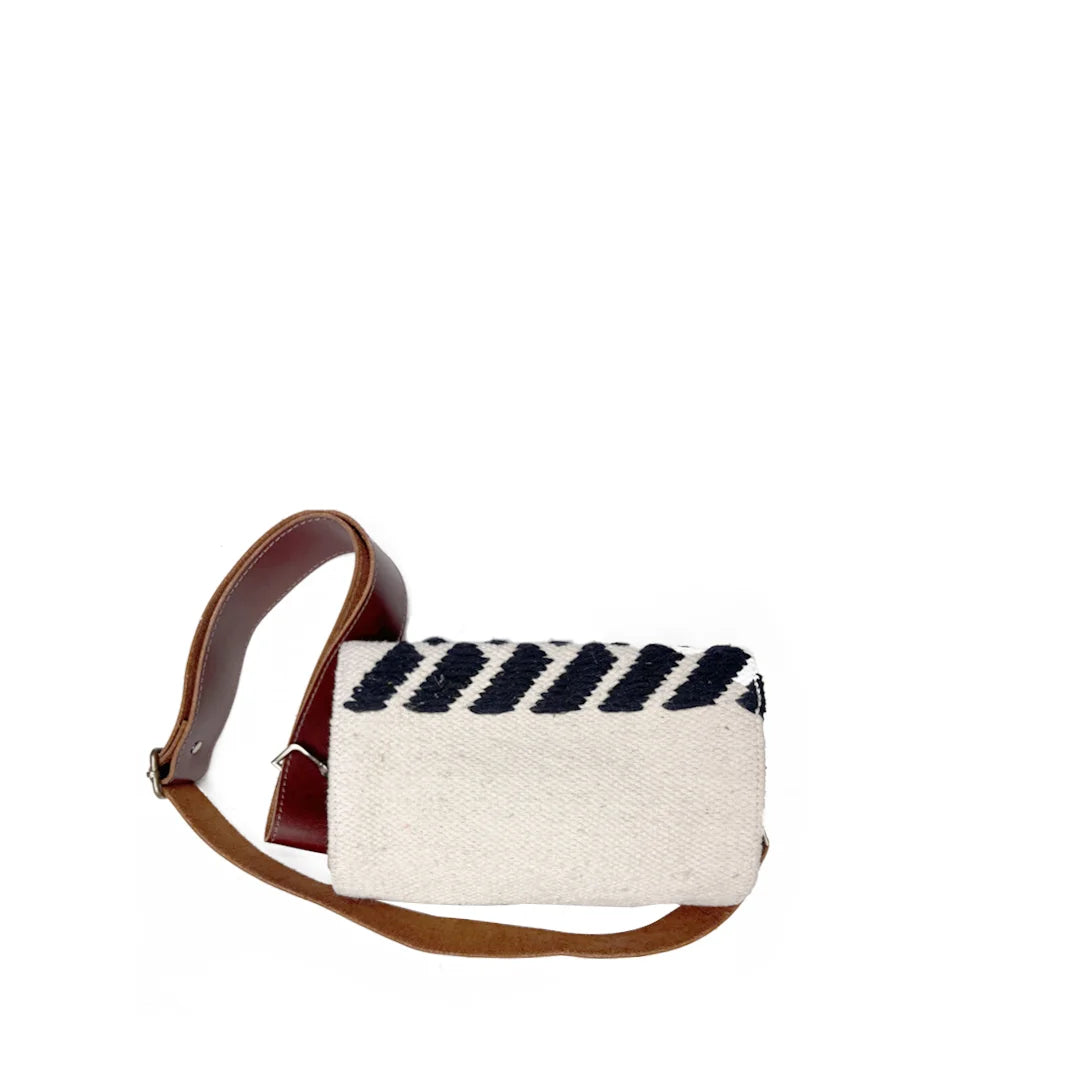 "A top view of a cream-colored woven bag with black stripes and a brown leather strap, positioned on a white surface. The image highlights the bag's clean lines and textured fabric."