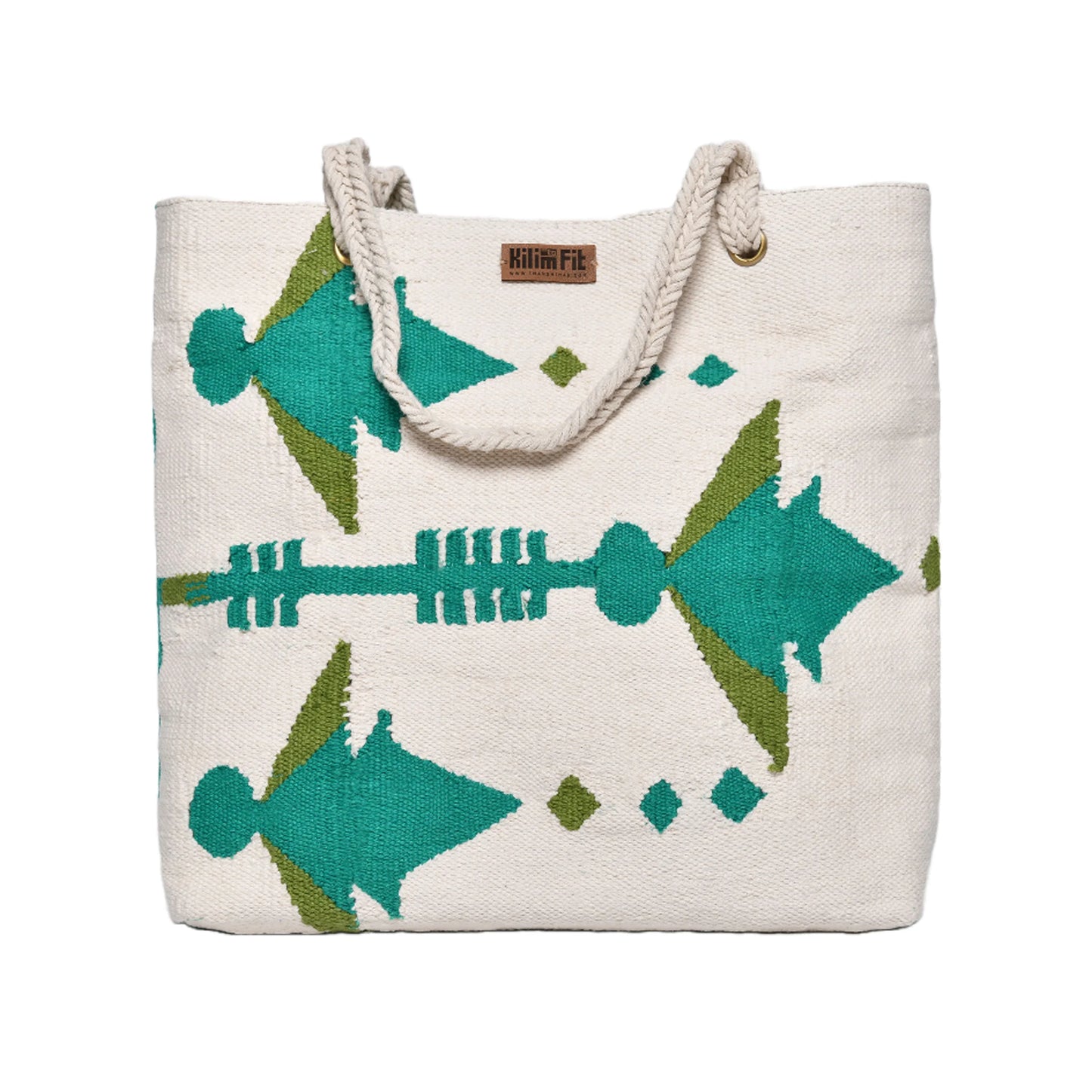 This image features a large, woven tote bag made of natural-colored fabric with vibrant geometric patterns in teal and green. The bag has sturdy rope handles and a small leather tag that reads "KilimFit." The design includes stylized figures and arrows, giving it a unique and artistic appearance.