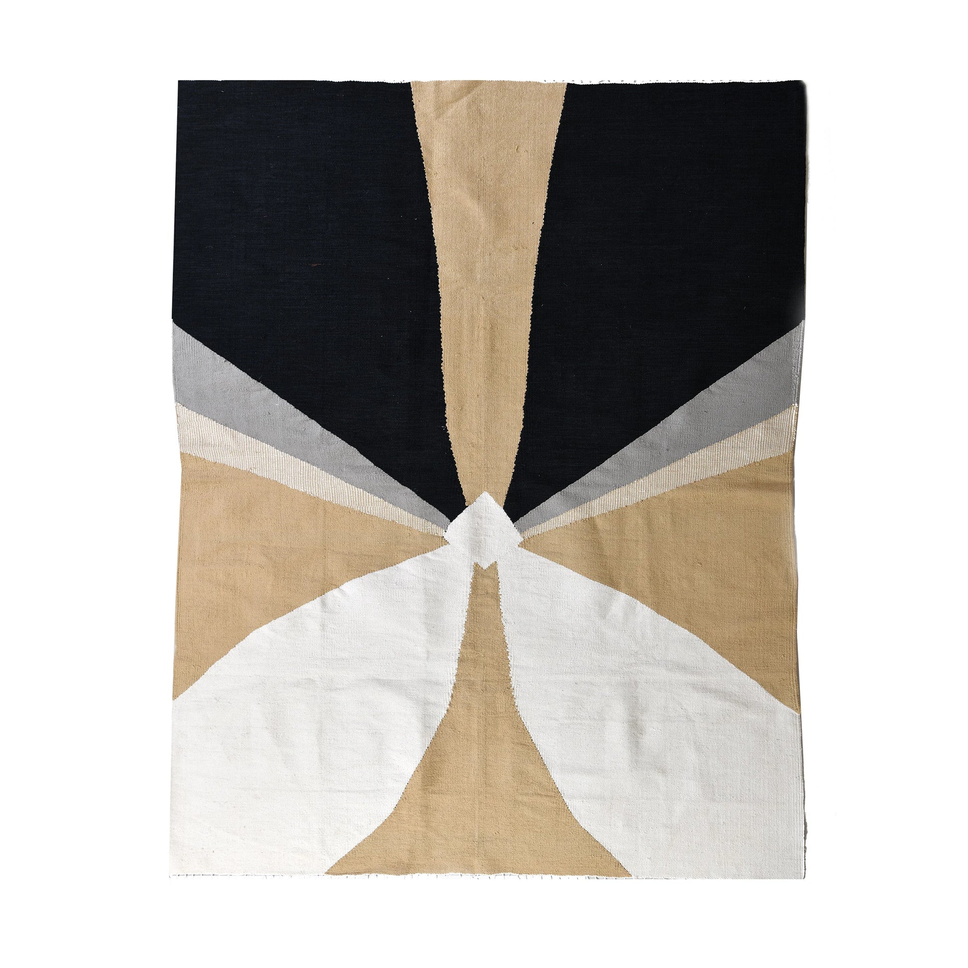 This image features a textile design with a geometric pattern. The fabric is divided into sections of various colors, including black, beige, gray, and white, creating a visually striking and abstract composition. The design resembles a stylized, symmetrical shape that radiates from the center toward the edges.