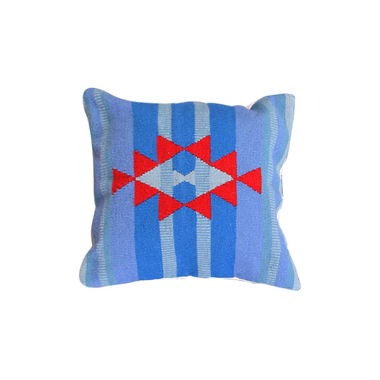 A square decorative pillow featuring a geometric pattern. The pillow has a blue and light blue striped background with a central design made up of red triangles and a diamond shape in the middle. The overall design is vibrant and colorful, adding a cozy touch to any space.