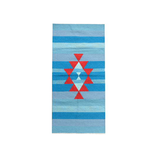 A rectangular area rug featuring a geometric design with alternating blue and cream stripes, highlighted by a central red diamond pattern. The rug's vibrant colors and bold shapes create a striking visual impact, suitable for enhancing modern interior decor.