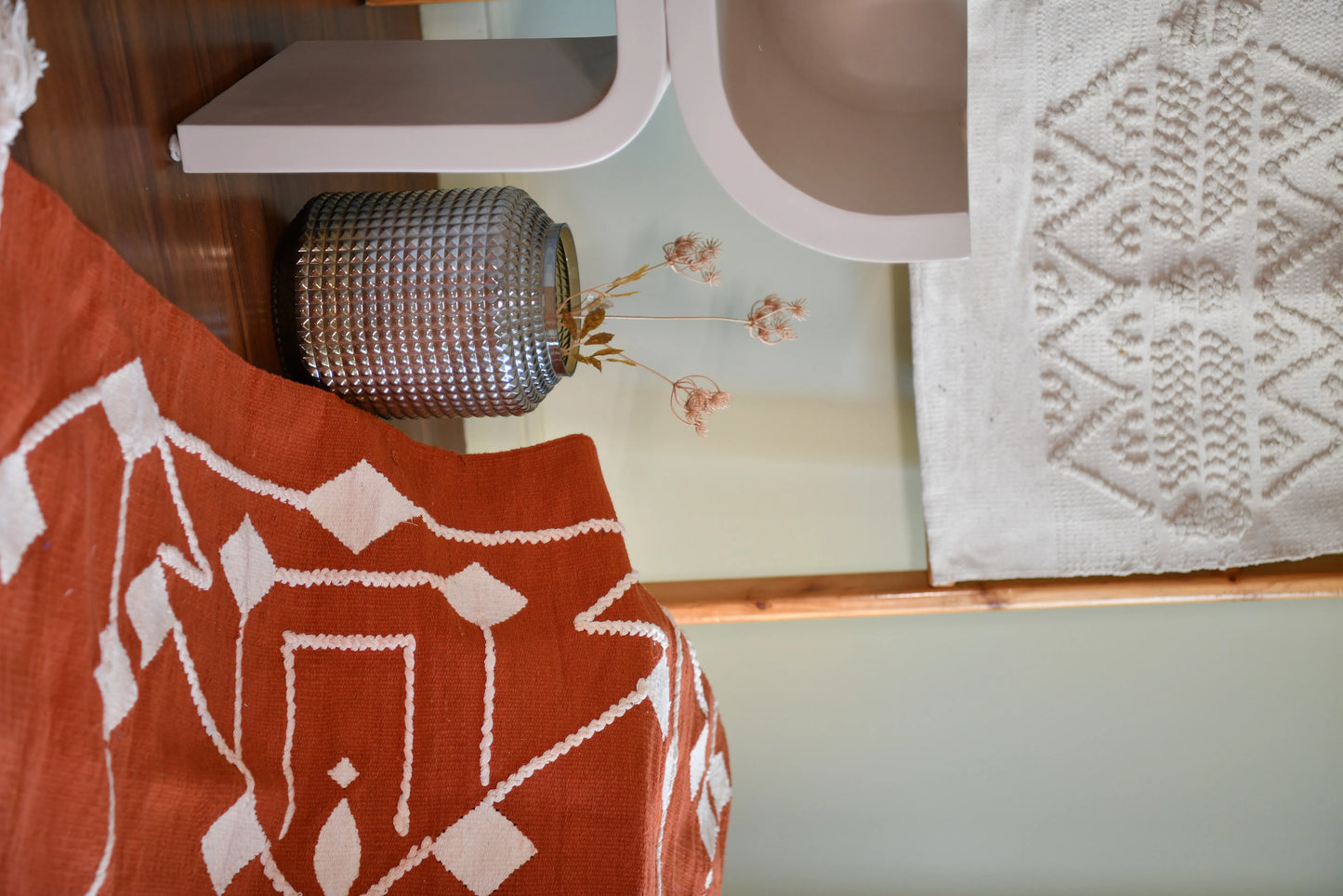 This 1 x 1.5 meter rug features a bold, Coral background and a striking white geometric pattern that consists of interconnected diamond shapes, creating a visually engaging composition. The edges are adorned with fringed tassels made of the same material, contributing to the traditional and artisanal aesthetic.