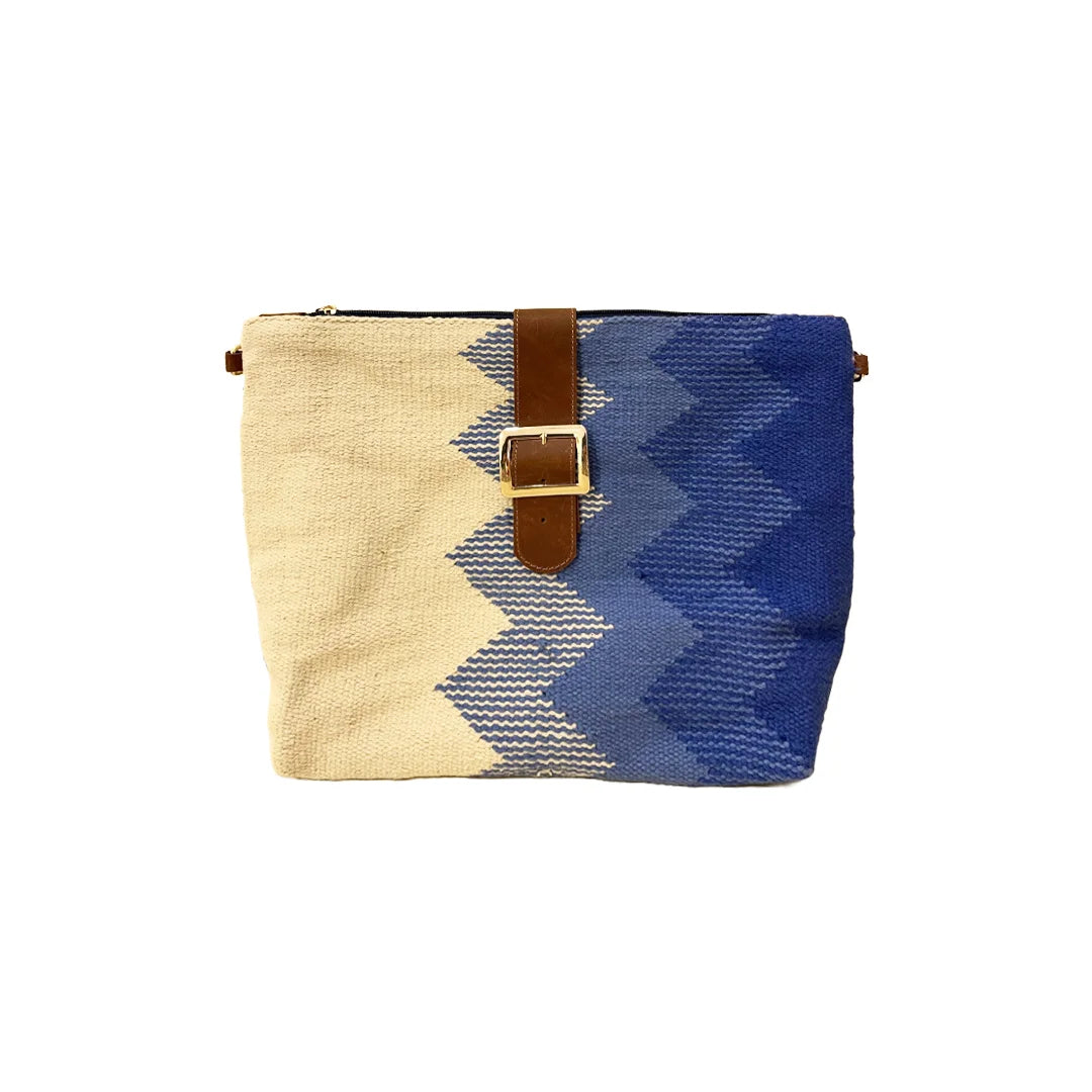 "A stylish, multicolored woven handbag featuring a mix of beige and blue hues in a zigzag pattern. The bag has a top zipper closure and a leather strap with a buckle detail, highlighting a contemporary and artistic design."