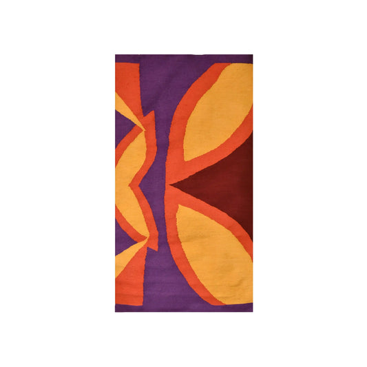 Abstract textile artwork featuring bold geometric shapes in vibrant colors, including deep purple, red, orange, and yellow. The design showcases symmetrical patterns that create a sense of movement and depth.