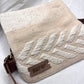 "A close-up of the front of a cream-colored woven bag with a white chevron pattern and a leather tag embossed with 'KUFUF.' The image focuses on the bag's texture and craftsmanship."