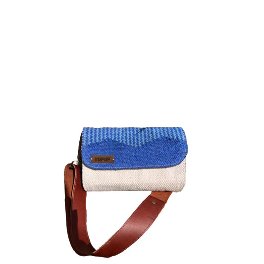 A woven handbag is displayed against a white background, featuring a vibrant blue top half and a cream bottom. The bag has a brown leather strap and a small metal brand tag that reads "KUFUF," emphasizing its stylish design.